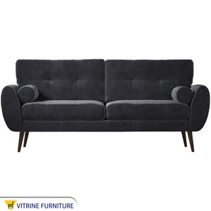 A high black sofa on elegant wooden legs