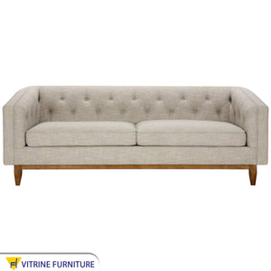 A beige sofa with capotonite grains, with armrests and backrest