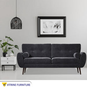 A high black sofa on elegant wooden legs