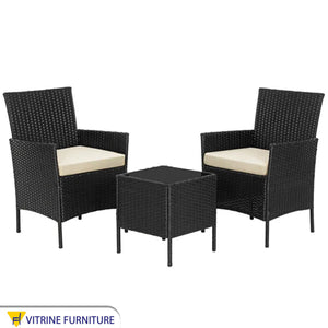 An outdoor set of 2 black chairs and a table