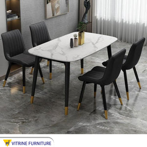 A white dining table and four black chairs