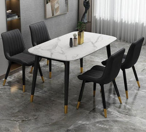 A white dining table and four black chairs