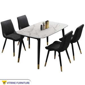 A white dining table and four black chairs