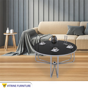 Circular table with three-legged chassis and black glass