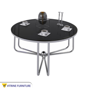 Circular table with three-legged chassis and black glass