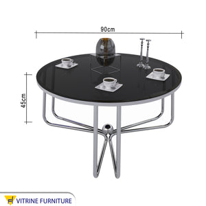 Circular table with three-legged chassis and black glass