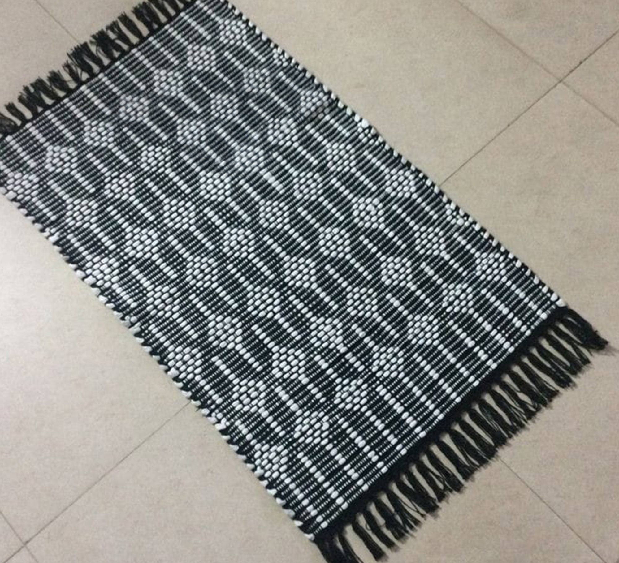 A black rug with white patterns and elegant fringe. - Vitrine Furniture - Accessories